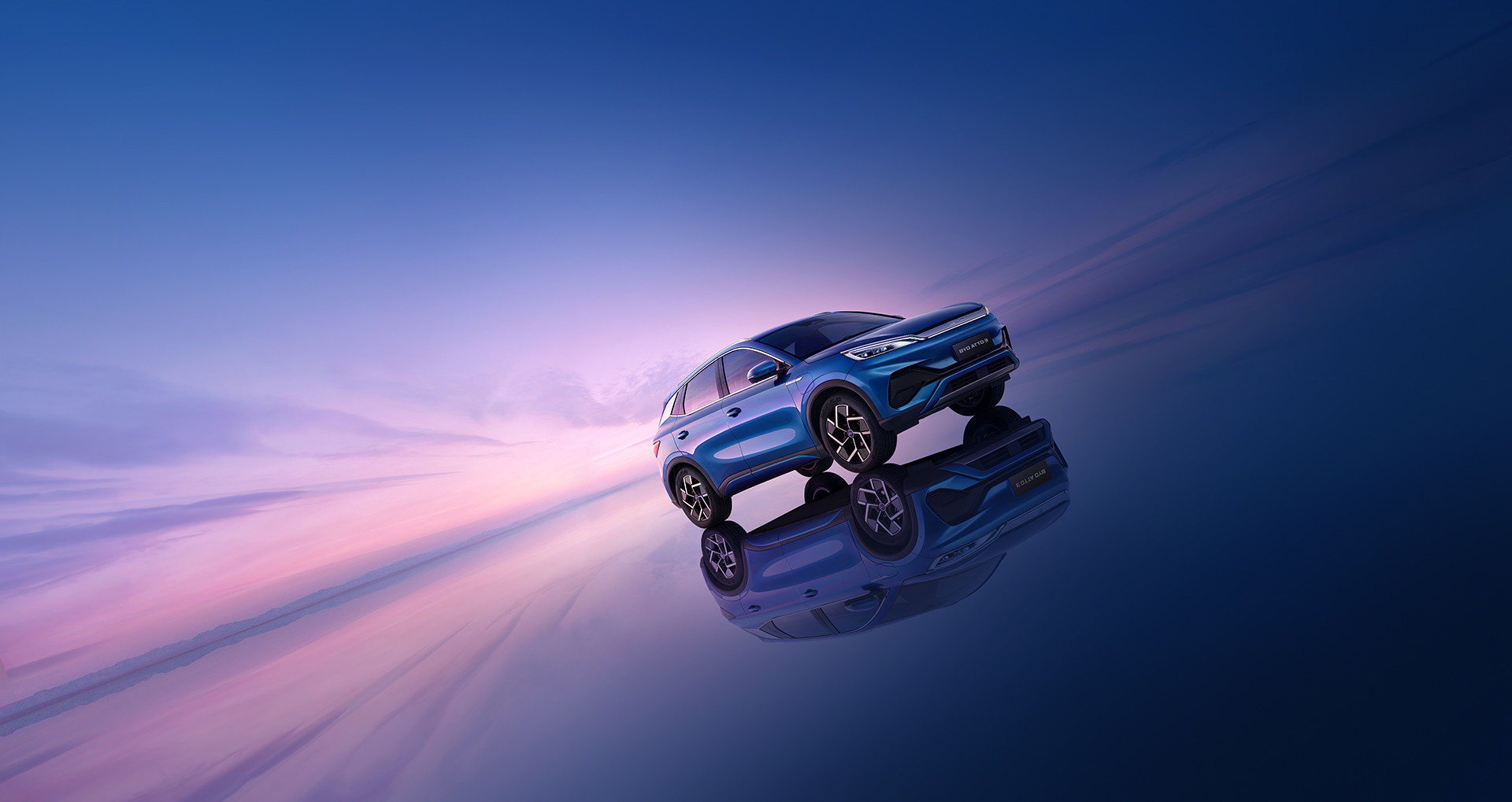 A dynamic stylised photograph of a Surfing Blue BYD Atto 3 parked on a reflective surface at a 45 degree angle with a beautiful sunset in the background