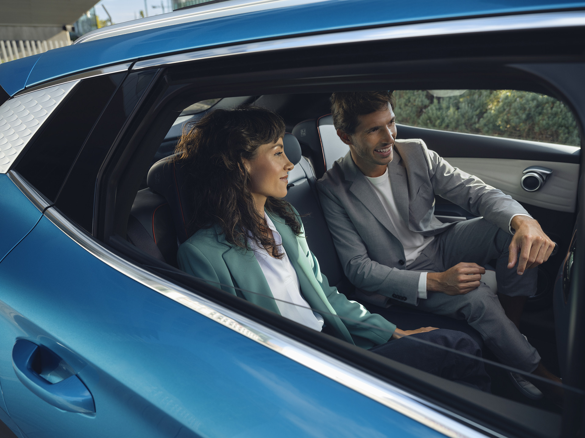 A photograph of two passengers sitting in the rear of a Surfing Blue BYD Atto 3